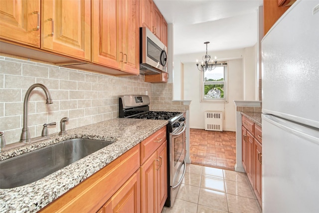 33 Barker Ave Unit 6K, White Plains, NY 10601 - kitchen with appliances with stainless steel finishes, radiator, light stone counters, and backsplash