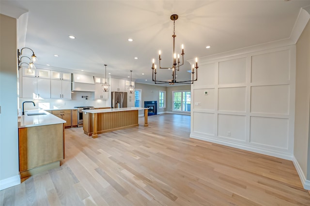 100 Root Ave, Islip, NY 11751 - kitchen with stainless steel appliances, wall chimney exhaust hood, a decorative wall, open floor plan, and a chandelier