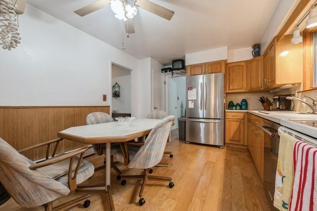 1581 Shirley Ct, North Merrick, NY 11566 - kitchen with appliances with stainless steel finishes, a wainscoted wall, light countertops, ceiling fan, and light wood finished floors
