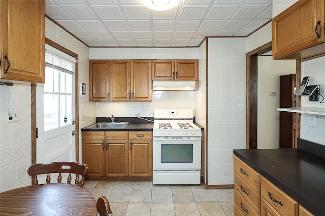2199 Mcarthur St, East Meadow, NY 11554 - kitchen with white range with gas cooktop, under cabinet range hood, brown cabinets, an ornate ceiling, and dark countertops