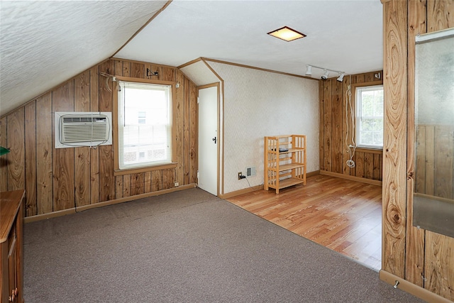 2199 Mcarthur St, East Meadow, NY 11554 - additional living space with healthy amount of natural light, vaulted ceiling, wood walls, a wall mounted AC, and wood finished floors