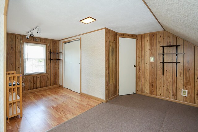 2199 Mcarthur St, East Meadow, NY 11554 - bonus room with wood walls, vaulted ceiling, wood finished floors, and a textured ceiling