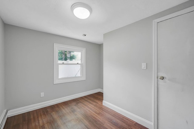 5439 Expressway Dr N, Holtsville, NY 11742 - empty room with wood finished floors and a baseboard heating unit