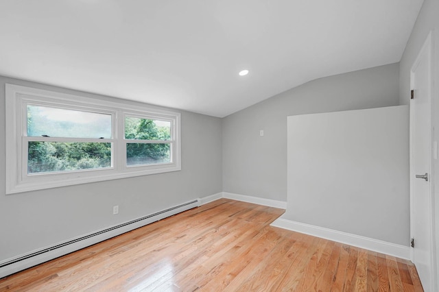 5439 Expressway Dr N, Holtsville, NY 11742 - empty room featuring a baseboard heating unit, vaulted ceiling, light wood finished floors, healthy amount of natural light, and recessed lighting
