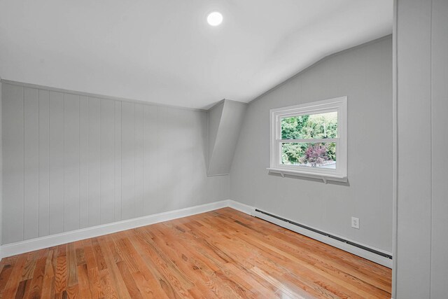 5439 Expressway Dr N, Holtsville, NY 11742 - spare room featuring a baseboard heating unit, vaulted ceiling, and light wood-style flooring