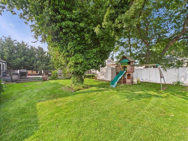 554 S 8th St, Lindenhurst, NY 11757 - fenced backyard featuring a playground, a deck, and a storage unit
