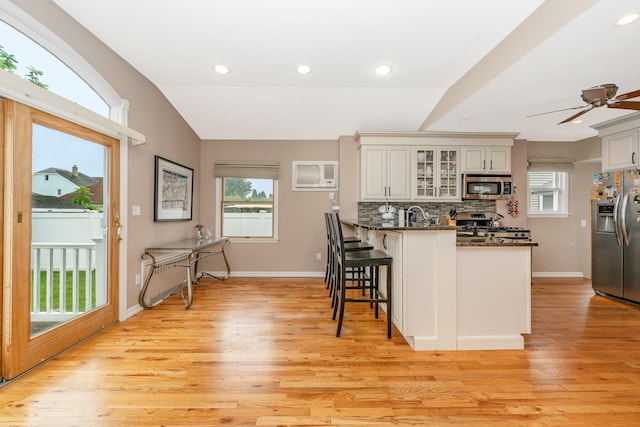 40 Syracuse St, Williston Park, NY 11596 - kitchen featuring stainless steel appliances, a peninsula, a kitchen breakfast bar, light wood-style floors, and glass insert cabinets