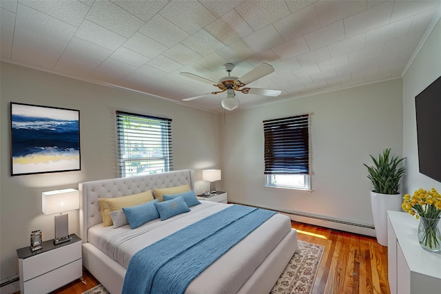 926 9th St, West Babylon, NY 11704 - bedroom featuring ornamental molding, a baseboard radiator, light wood-type flooring, a ceiling fan, and baseboard heating