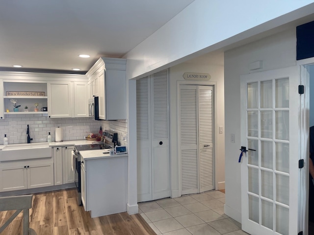 892 Skyline Dr Unit 892, Coram, NY 11727 - kitchen with electric stove, stainless steel microwave, backsplash, light countertops, and white cabinets