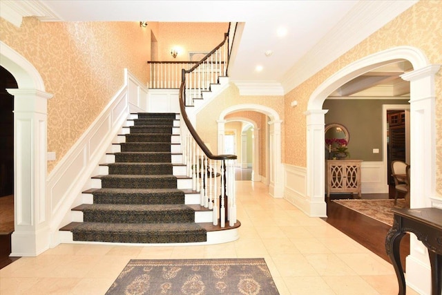 1616 Stewart Ln, Laurel Hollow, NY 11791 - stairway featuring a decorative wall, arched walkways, wallpapered walls, a wainscoted wall, and crown molding