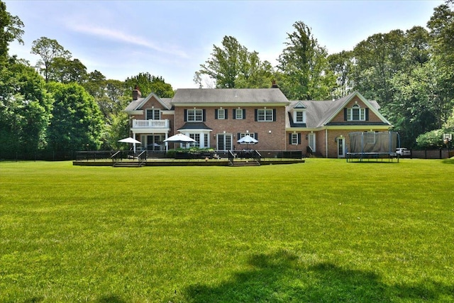 1616 Stewart Ln, Laurel Hollow, NY 11791 - rear view of house featuring a trampoline, a deck, a yard, and a chimney