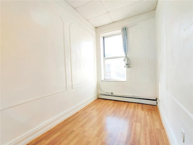 1363 64th St, Brooklyn, NY 11219 - unfurnished room with a baseboard radiator, a drop ceiling, and light wood-type flooring