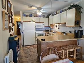 56 Pameeches Path, East Moriches, NY 11940 - kitchen with white appliances, a peninsula, a ceiling fan, a breakfast bar, and light countertops