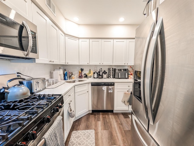 15 Fairview Cir, Middle Island, NY 11953 - kitchen featuring stainless steel appliances, wood finished floors, tasteful backsplash, white cabinetry, and light countertops