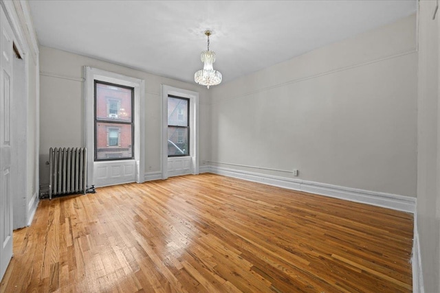 176 W 81st St Unit 3E, New York Manhattan, NY 10024 - spare room featuring radiator heating unit, a chandelier, and light wood finished floors