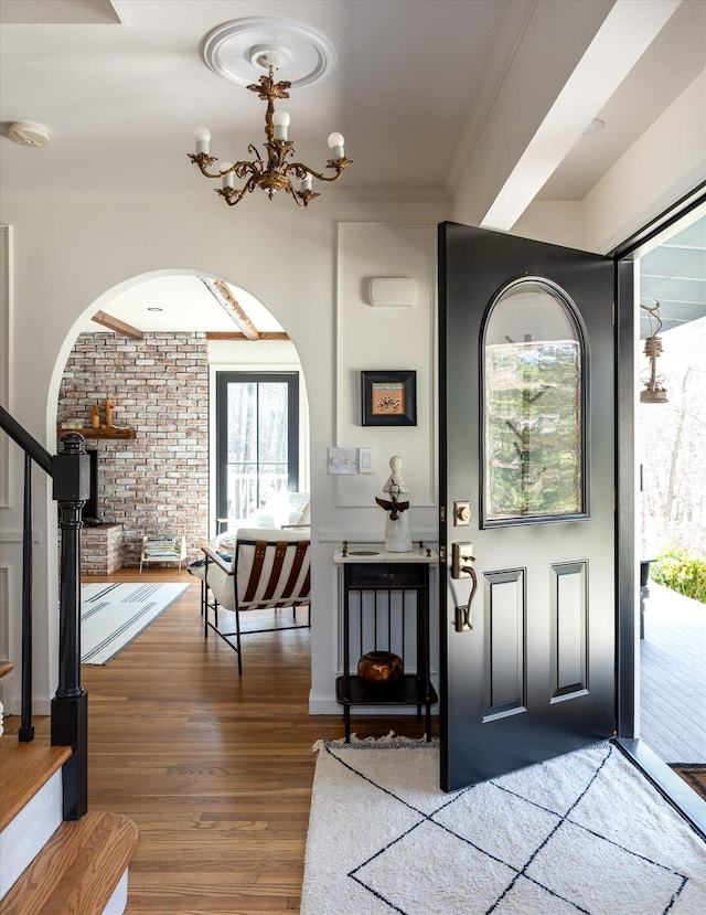 8 Maclean Dr, Pound Ridge, NY 10576 - entrance foyer with arched walkways, brick wall, wood finished floors, a chandelier, and stairway