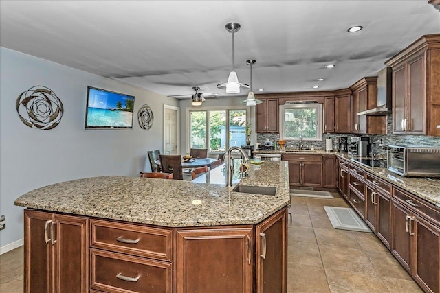 7 Woodstock Pl, Lake Grove, NY 11755 - kitchen with wall chimney exhaust hood, an island with sink, backsplash, light stone counters, and light tile patterned flooring