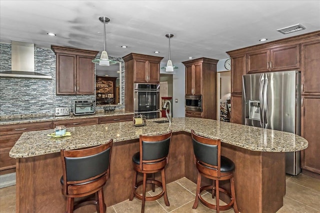 7 Woodstock Pl, Lake Grove, NY 11755 - kitchen featuring wall chimney range hood, light tile patterned flooring, appliances with stainless steel finishes, decorative backsplash, and a center island with sink