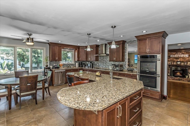 7 Woodstock Pl, Lake Grove, NY 11755 - kitchen with stainless steel appliances, wall chimney exhaust hood, backsplash, a kitchen island with sink, and ceiling fan