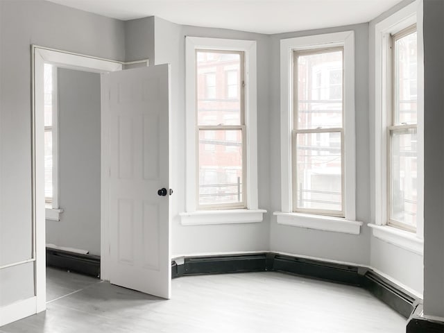 12 Liberty St, Newburgh, NY 12550 - empty room featuring plenty of natural light, wood finished floors, and a baseboard radiator