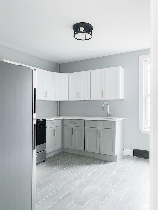 12 Liberty St, Newburgh, NY 12550 - kitchen featuring freestanding refrigerator, stove, light countertops, and white cabinetry