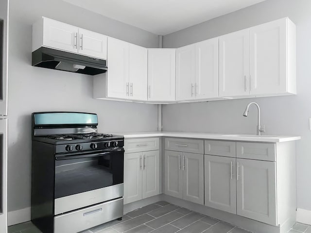 12 Liberty St, Newburgh, NY 12550 - kitchen featuring stainless steel gas range oven, under cabinet range hood, light countertops, and white cabinetry