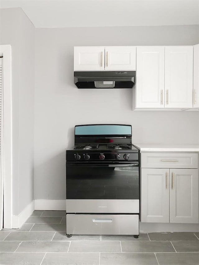 12 Liberty St, Newburgh, NY 12550 - kitchen with stainless steel range with gas stovetop, under cabinet range hood, white cabinetry, light countertops, and light tile patterned flooring