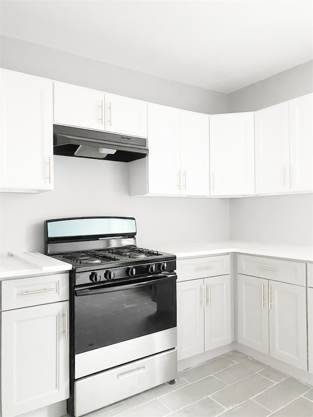 12 Liberty St, Newburgh, NY 12550 - kitchen with gas stove, under cabinet range hood, white cabinetry, light countertops, and light tile patterned floors
