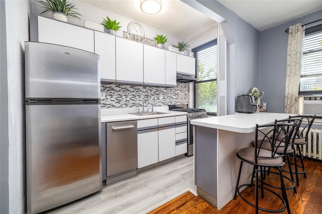 12 Hempstead Ave Unit 1G, Rockville Centre, NY 11570 - kitchen featuring stainless steel appliances, light wood-style flooring, white cabinets, light countertops, and a breakfast bar area
