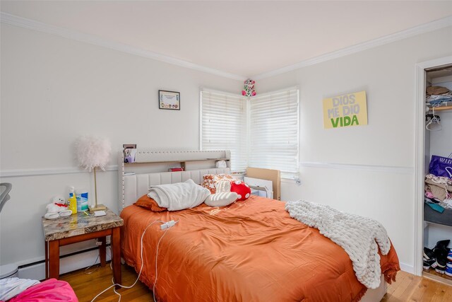 556 Long Beach Rd, Island Park, NY 11558 - bedroom featuring wood finished floors, crown molding, and a baseboard heating unit