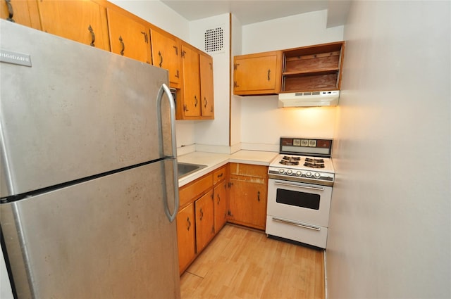 281 Garth Rd Unit B5D, Scarsdale, NY 10583 - kitchen featuring freestanding refrigerator, white gas range, under cabinet range hood, light wood-style floors, and light countertops