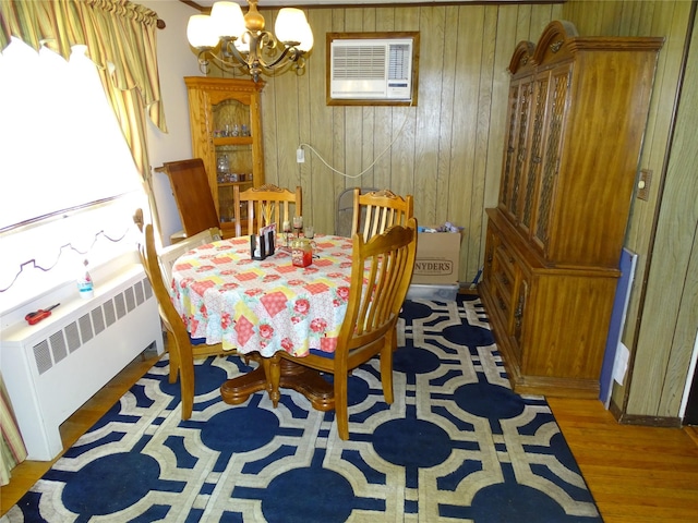 524 Polaris St, North Babylon, NY 11703 - dining area featuring radiator, a chandelier, wood walls, wood finished floors, and a wall unit AC