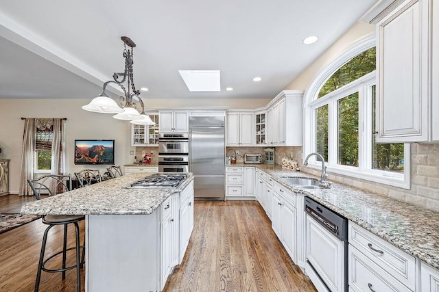 17 Dunmore Rd, New City, NY 10956 - kitchen featuring stainless steel appliances, a skylight, a breakfast bar area, white cabinets, and backsplash