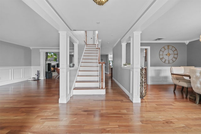 25 Bellwood Dr, New City, NY 10956 - entryway featuring a decorative wall, a warm lit fireplace, crown molding, stairs, and wood finished floors