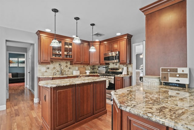 25 Bellwood Dr, New City, NY 10956 - kitchen with appliances with stainless steel finishes, light wood-style floors, backsplash, light stone counters, and brown cabinets