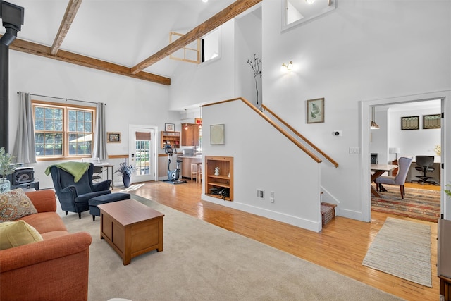 62 Guymard Tpke, Godeffroy, NY 12729 - living room with a wood stove, a towering ceiling, stairway, light wood-type flooring, and beam ceiling