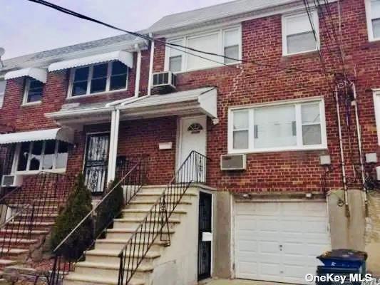 5-39 117th St, Flushing, NY 11356 - view of property featuring brick siding, a garage, and an AC wall unit