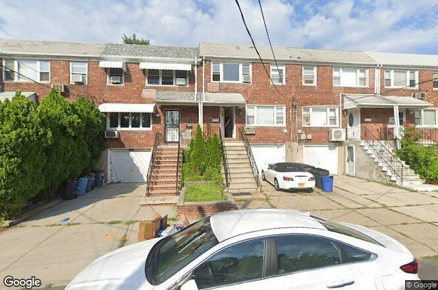5-39 117th St, Flushing, NY 11356 - view of property with stairs, an attached garage, brick siding, and driveway