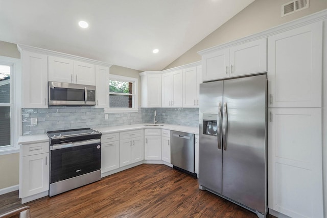 12 Bay Ave, Lake Ronkonkoma, NY 11779 - kitchen featuring appliances with stainless steel finishes, light countertops, vaulted ceiling, backsplash, and white cabinetry