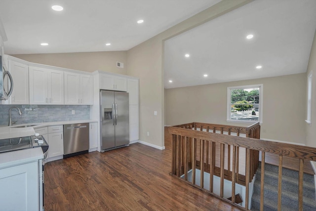 12 Bay Ave, Lake Ronkonkoma, NY 11779 - kitchen with stainless steel appliances, lofted ceiling, dark wood-type flooring, decorative backsplash, and white cabinetry