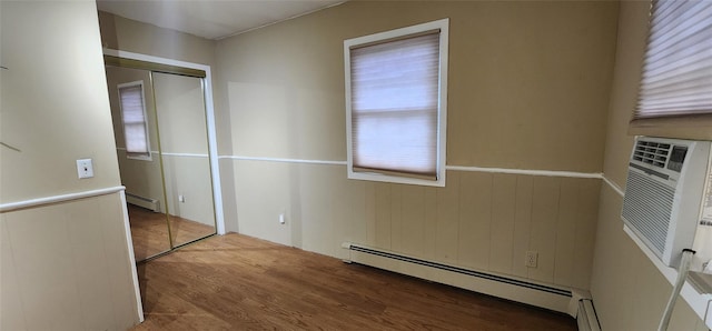 76 Gooseberry Rd, Mastic Beach, NY 11951 - unfurnished bedroom featuring a baseboard heating unit, wood finished floors, a closet, and a wainscoted wall