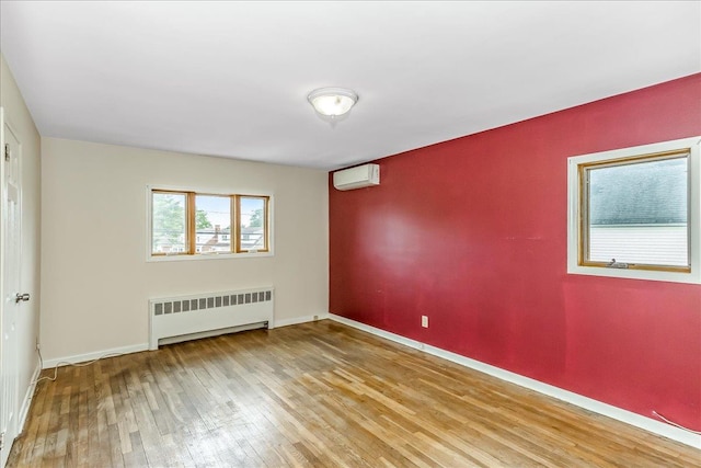 165 Wheeler Ave, Valley Stream, NY 11580 - unfurnished room featuring radiator heating unit, a wall unit AC, and hardwood / wood-style flooring