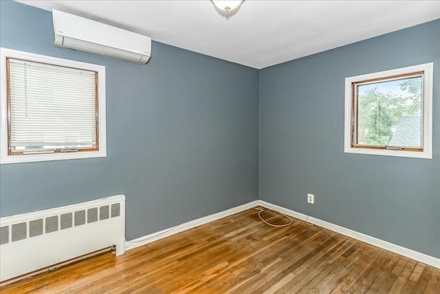 165 Wheeler Ave, Valley Stream, NY 11580 - spare room featuring radiator, an AC wall unit, and hardwood / wood-style flooring