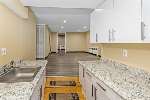 165 Wheeler Ave, Valley Stream, NY 11580 - kitchen featuring radiator, light wood-style floors, white cabinets, recessed lighting, and light stone counters