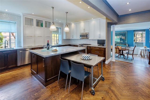 3001 Henry Hudson Pkwy Unit 1Fg, Bronx, NY 10463 - kitchen featuring appliances with stainless steel finishes, white cabinetry, a kitchen island, ornamental molding, and light stone counters