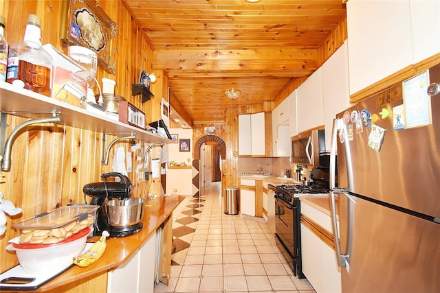 517 Westchester Ave, Mount Vernon, NY 10552 - kitchen with stainless steel appliances, wood ceiling, white cabinetry, light countertops, and wooden walls