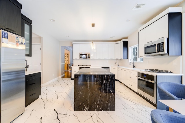 83 N Airmont Rd, Suffern, NY 10901 - kitchen featuring appliances with stainless steel finishes, light marble finish flooring, dark cabinetry, a center island, and recessed lighting