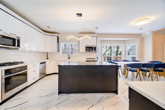 83 N Airmont Rd, Suffern, NY 10901 - kitchen with stainless steel appliances, light marble finish flooring, healthy amount of natural light, and decorative light fixtures