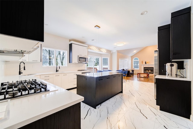 83 N Airmont Rd, Suffern, NY 10901 - kitchen featuring appliances with stainless steel finishes, a center island, a lit fireplace, open floor plan, and light countertops