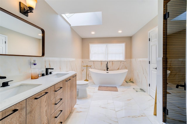 83 N Airmont Rd, Suffern, NY 10901 - bathroom featuring a skylight, double vanity, tile walls, wainscoting, and a soaking tub